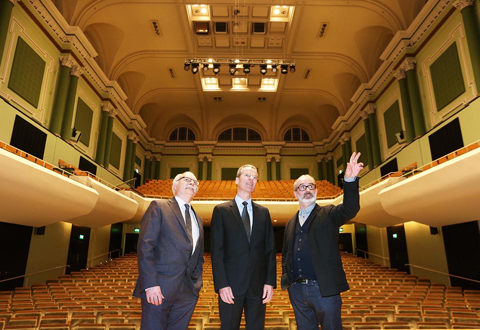 Three people standing in concert hall