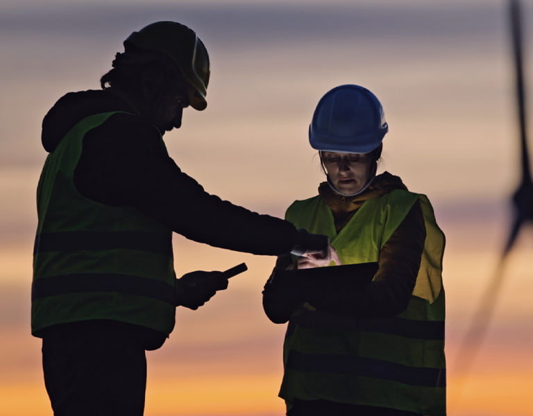 Corporate sustainability image of two workers in front of a windmill