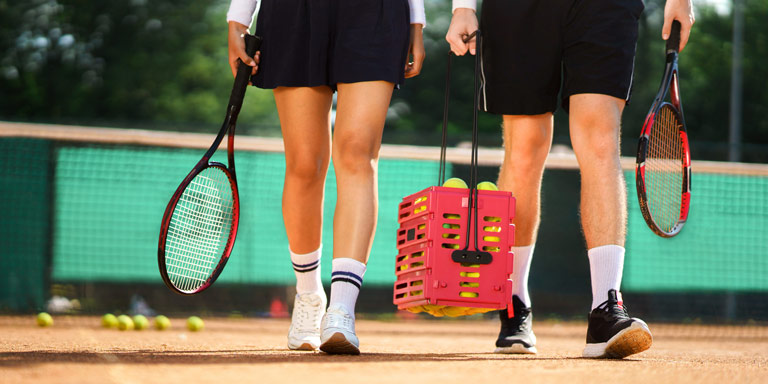 Man and woman walking onto tennis court